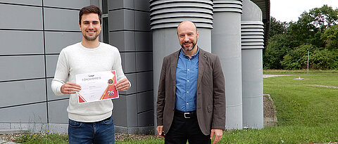The award-winning computer scientist Martin Sträßer and Professor Samuel Kounev showing the certificate awarded for the outstanding Master's thesis.