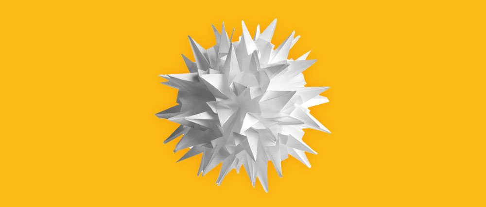 weißer Papierball mit Nadeln auf gelbem Hintergrund