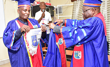 Überreichung der Universitäts-Insignien durch den Rektor Alexis Mpoyi stellvertretend an den Secrétaire Général Académique Guy Octave Lutumba.