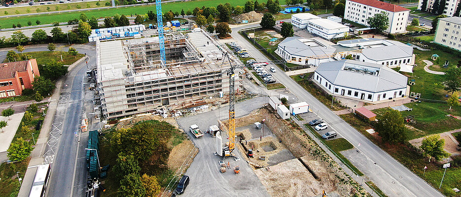 Die Baugrube für den Neubau des DZPP. Direkt dahinter der Rohbau für ein neues Wohnheim des Studentenwerks, rechts die Waben des Kinder- und Familienzentrums der Universität.