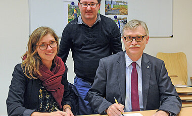 Kanzler Uwe Klug und Madeleine Leube unterscheiben die Patenschaftsvereinbarung zur Beschäftigung von Christoph Nölke. (Foto: Robert Emmerich)