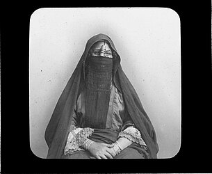 Hier sieht man ein Diabild, welches eine Ägyptische Frau mit Gesichtsschleier darstellt. Es ist eine schwarz-weiß Fotografie.