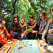 Das Foto zeigt Studierende mit Schüler:innen bei einem Workshop zum Thema Handy und Regenwald. 