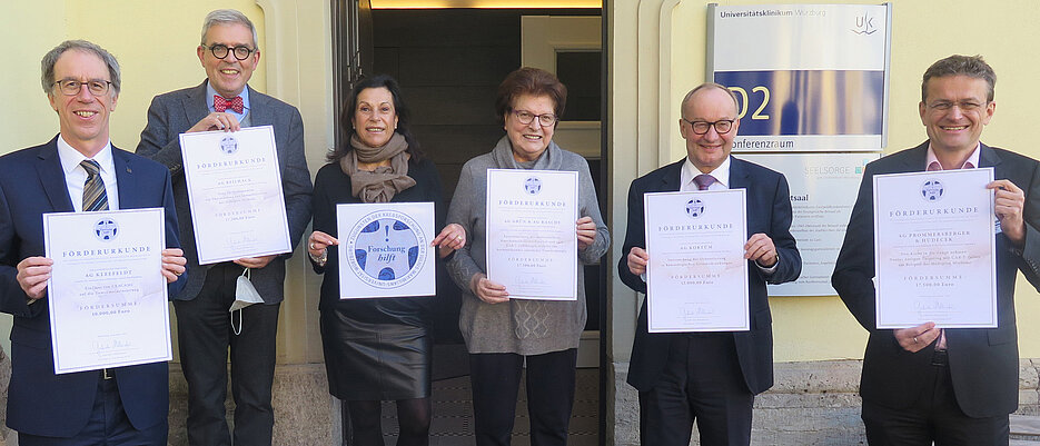           JMU-Präsident Paul Pauli, Medizin-Dekan Matthias Frosch, Gabriele Nelkenstock, Barbara Stamm und Professor Hermann Einsele als Vertreterinnen und Vertreter des Stiftungsrates der Stiftung „Forschung hilft“ präsentieren mit dem Ärztlichen Direktor des Uniklinikums Würzburg, Jens Maschmann, die Förderurkunden für die neu unterstützten Krebsforschungsprojekte.