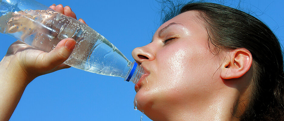 Frau, die aus einer Flasche Wasser trinkt