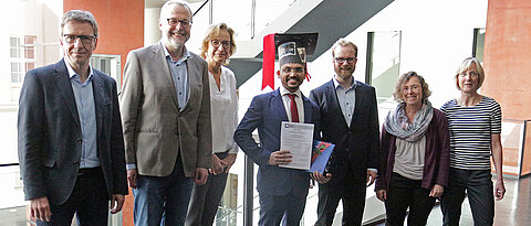 Dr. Hardikkumar Jetani (Mitte) mit dem Promotionskomitee und Vertreterinnen der Graduate School (v.l.): Prüfungsvorsitzender Professor Thomas Rudel, Professor Thomas Herrmann, PD Dr. Friederike Berberich-Siebelt, Dr. Michael Hudecek, Dr. Gabriele Blum-Oehler, Professorin Caroline Kisker.