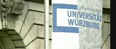 Uni-Fahnen vor dem Hauptgebäude am Sanderring: Ausschnitt aus dem Videoporträt der Uni Würzburg.