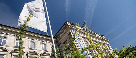 Fahnen vor dem Hauptgebäude der Uni Würzburg. Foto: Daniel Peter