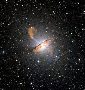Colour composite image of Centaurus A, revealing the lobes and jets emanating from the active galaxy’s central black hole. This is a composite of images obtained with three instruments, operating at very different wavelengths. The 870-micron submillimetre data, from LABOCA on APEX, are shown in orange. X-ray data from the Chandra X-ray Observatory are shown in blue. Visible light data from the Wide Field Imager (WFI) on the MPG/ESO 2.2 m telescope located at La Silla, Chile, show the stars and the galaxy’s characteristic dust lane in close to "true colour". #L