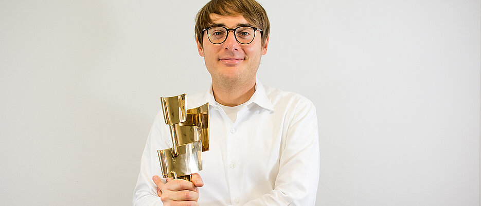 Preisträger Philipp Gieg mit der Bronzestatue „Gedankenblitz“.