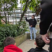 Ein Student zeigt den Schüler:innen die Früchte des Kakaobaums.