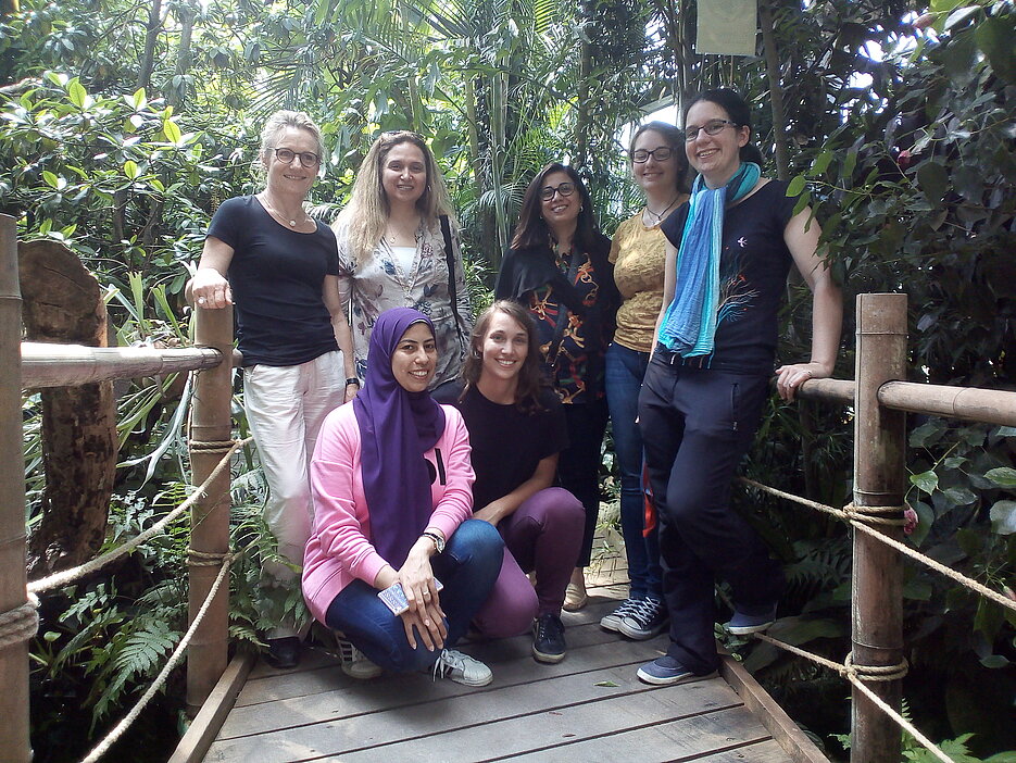 Besuch aus Kairo, Gruppenbild im Gewächshaus. 3 Gastwissenschaftlerinnen, 2 Studierende der Museologie sowie Simone Doll-Gerstendörfer und Dr. Kerstin Bissinger stehen auf einem Steg im Gewächshaus