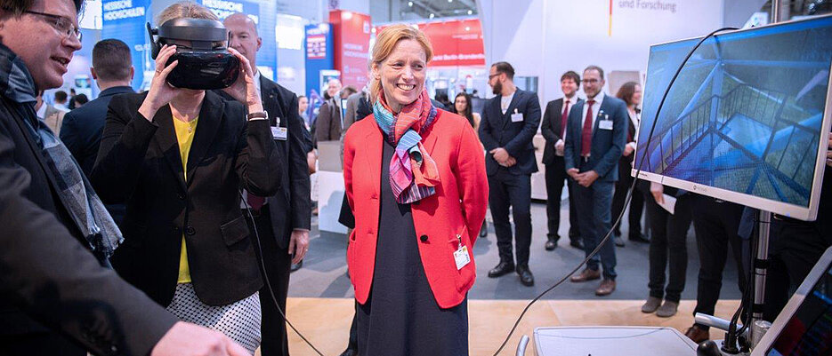 Bundesforschungsministerin Anja Karliczek (mit VR-Brille) am Stand von EVElyn auf der Hannovermesse. Links Mathias Müller, Geschäftsführer von VTplus, rechts Karin Prien, Bildungsministerin in Schleswig-Holstein.