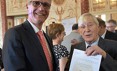 Guido Kirchmayer (links) schloss vor 25 Jahren sein VWL-Studium in Würzburg ab. Das Alumni-Jubilarzertifikat bekam er von Theodor Berchem überreicht, dem Vorsitzenden des Alumni-Vereins.