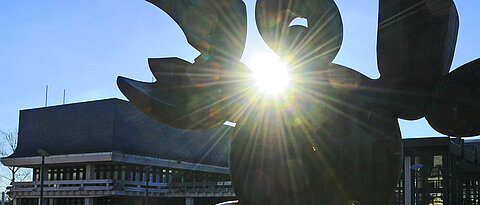 Sonne scheint durch eine Skulptur auf dem Uni-Campus in Würzburg. 