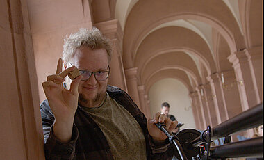Peter Collin, Student an der Uni Bayreuth, untersützte als Kameramann. Im Bild übergibt er den Spielenden einen Stein aus der eben durchbrochenen "vierten Wand" als Belohnung. 