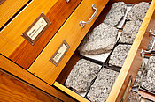 Hier sieht man einen Holzkasten, in dem sich verschiedene Granit Gesteine befinden. 