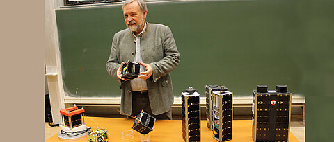 Klaus Schilling mit einigen der Kleinsatelliten, die in seinem Team zusammen mit Studierenden entwickelt wurden.