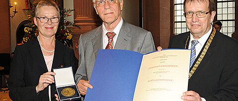 Herbert Wellhöfer bekommt von Universitätspräsident Alfred Forchel (r.) und Vizepräsidentin Barbara Sponholz die Röntgenmedaille überreicht. (Foto: Robert Emmerich)