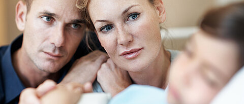 Anxious parents watching their daughter sleep as she lies in a deep coma