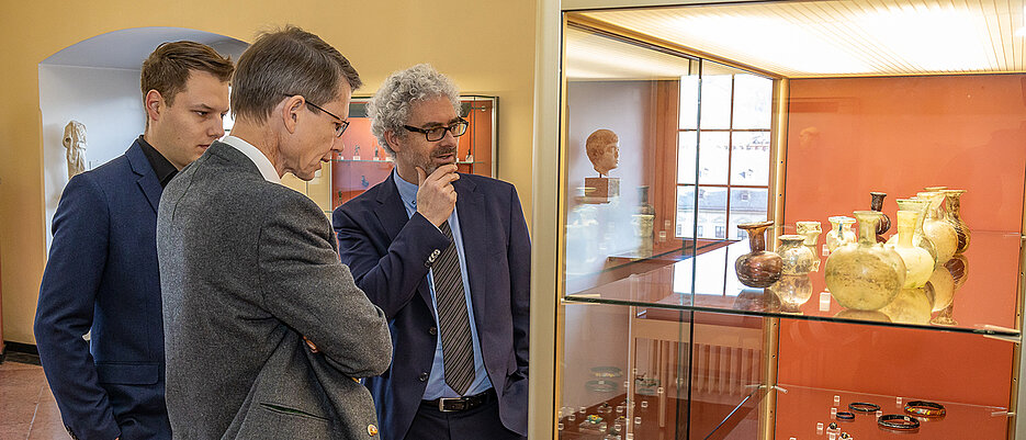 Betrachten eine Vitrine mit antiken Gläsern (v.l.) Jan Soldin, Direktor des Museums Otto Schäfer, Sebastian Remelé, Oberbürgermeister von Schweinfurt, und Jochen Griesbach-Scriba, Direktor der Antikenabteilung des Martin von Wagner Museums.