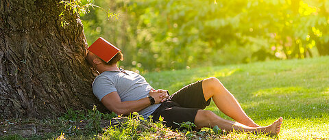 Man, sitting under a tree, taking a nap