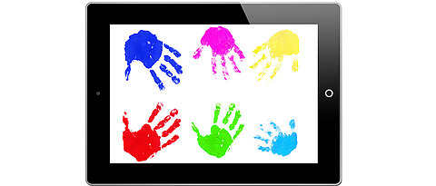 Kinderhände sind auf einem Tablet zu sehen.