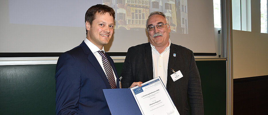Dieter Buchheidt, Vorsitzender der Deutschsprachigen Mykologischen Gesellschaft, überreicht die Urkunde des mit 5.000 Euro dotierten Forschungsförderpreises an den Preisträger 2018, Johannes Wagener. 