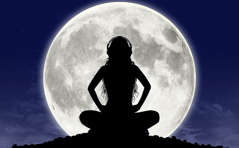 Women meditating in front of a full moon.