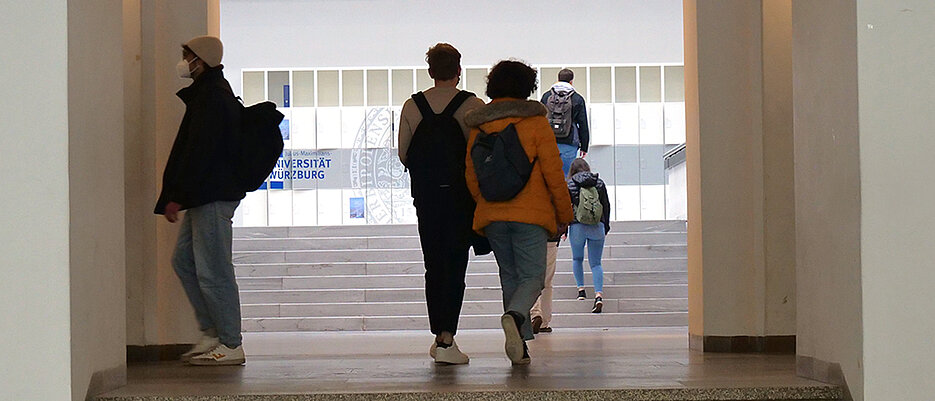 Studierende laufen im Unigebäude am Sanderring die Treppen hoch zur Vorlesung.