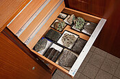 Hier sieht man einen Holzkasten, in dem sich verschiedene Eklogit Gesteine befinden. 