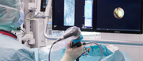 Den Stein im Blick: Bei der flexiblen Harnleiter- und Nierenspiegelung (URS) kann der Operateur mittels Röntgen (linker Bildschirm) und hochauflösender Kamera (rechter Bildschirm) im Operationsfeld genau navigieren, um auch schwierig gelegene Nierensteine aufzuspüren.