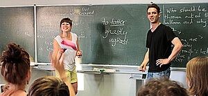 Foto: Marie-Isabell Schilk Szene aus Tutorium: Tutorin und Tutor stehen an der Tafel vor einigen Studierenden