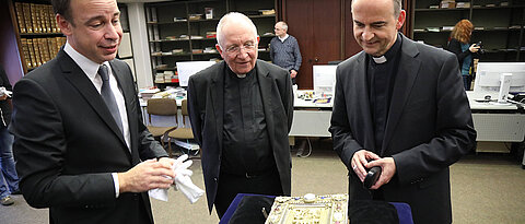Hans-Günter Schmidt (links), Leiter der Universitätsbibliothek, präsentiert Bischof Franz Jung (rechts) und Domprobst Weihbischof Ulrich Boom das Kiliansevangeliar.
