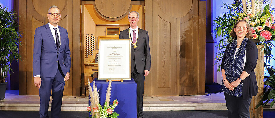 Peter Bofinger (l.) wurde auf dem Stiftungsfest 2021 die Julius-Maximillians-Verdienstmedaille verliehen. In der Mitte: Unipräsident Paul Pauli, rechts die Vizepräsidentin und Laudatorin Doris Fischer.