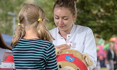 In der Teddyklinik lässt ein Mädchen seinen kranken Teddy behandeln.