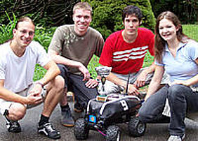 Das Würzburger Team (von links: Manuel Stahl, Daniel Eck, Martin Hess und Doris Aschenbrenner) mit dem Roboterfahrzeug Outdoor Merlin, das den Siegerpokal trägt. Foto: Institut für Informatik Das Würzburger Team (von links: Manuel Stahl, Daniel Eck, Martin Hess und Doris Aschenbrenner) mit dem Roboterfahrzeug Outdoor Merlin, das den Siegerpokal trägt. Foto: Institut für Informatik