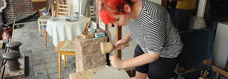 Wie in der Antike schlägt Eva Ruchti den Buchstaben „R“ mit Hammer und Meißel in eine Steintafel. (Foto: Judith Küfner)