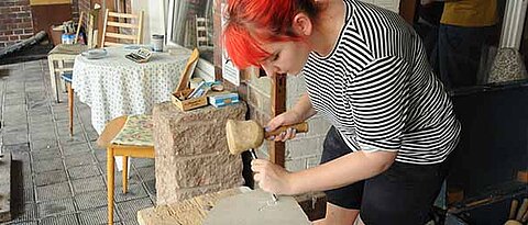 Wie in der Antike schlägt Eva Ruchti den Buchstaben „R“ mit Hammer und Meißel in eine Steintafel. (Foto: Judith Küfner)