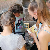 Kinder finden Hinweise und lösen am Tablet Rätsel.