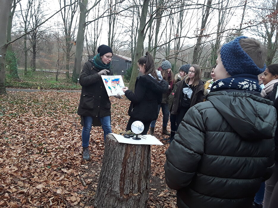 Studentin vermittelt Schülern das Klima und die Vegetation der gemäßigten Breiten im Buchenwald
