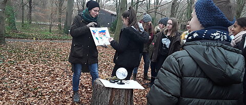 Studentin vermittelt Schülern das Klima und die Vegetation der gemäßigten Breiten im Buchenwald