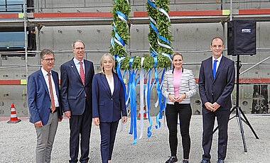 Die Rednerinnen und Redner, die beim Richtfest sprachen, mit der Richtkrone (v.l.): Christian Schuchardt, Paul Pauli, Grit Liebau, Judith Gerlach, Tobias Brixner.