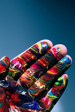 Innenfläche einer Hand, die mit verschiedenen Farben ganz bunt bemalt ist.