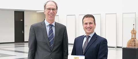 Giorgio Sangiovanni (rechts) ist neuer Professor am Würzburg-Dresdner Exzellenzcluster ct.qmat. Er hält die Berufungsurkunde in den Händen, die er am 10. Oktober 2023 vom Präsidenten der Universität Würzburg, Paul Pauli, erhalten hat.