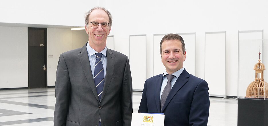 Giorgio Sangiovanni (rechts) ist neuer Professor am Würzburg-Dresdner Exzellenzcluster ct.qmat. Er hält die Berufungsurkunde in den Händen, die er am 10. Oktober 2023 vom Präsidenten der Universität Würzburg, Paul Pauli, erhalten hat.
