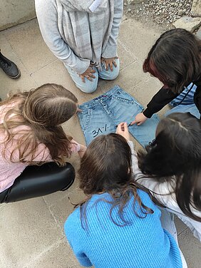 Die Schüler:innen diskutieren anhand eines "Jeans-Puzzles", wie sich der Preis einer Jeans zusammensetzt. (Foto: Emily Schweitzer-Martin)