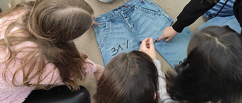Die Schüler:innen diskutieren anhand eines "Jeans-Puzzles", wie sich der Preis einer Jeans zusammensetzt. (Foto: Emily Schweitzer-Martin)