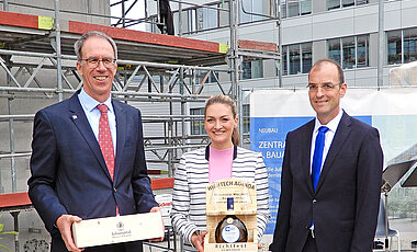 Ministerin Judith Gerlach erhielt von Unipräsident Paul Pauli (l.) und Dekan Tobias Brixner ein Geschenk.