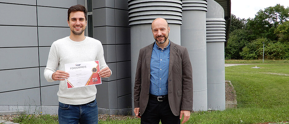 The award-winning computer scientist Martin Sträßer and Professor Samuel Kounev showing the certificate awarded for the outstanding Master's thesis.